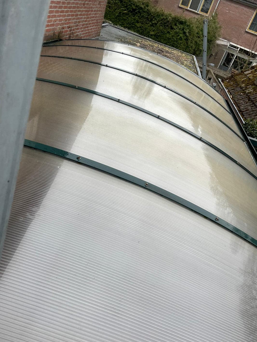 Dezelfde lichtdoorlatende overkapping met schonere platen na de reiniging.