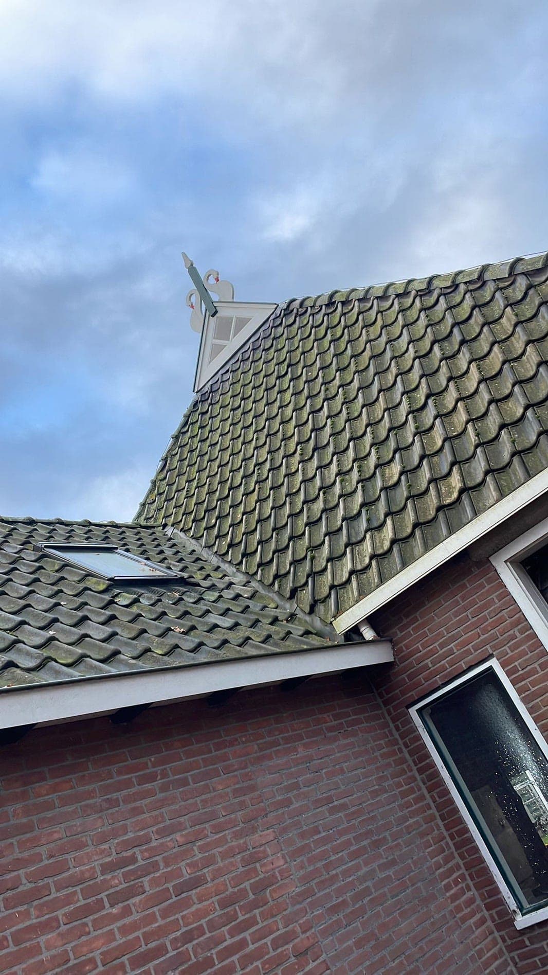 Donkere dakpannen rond een woning met dakkapel.