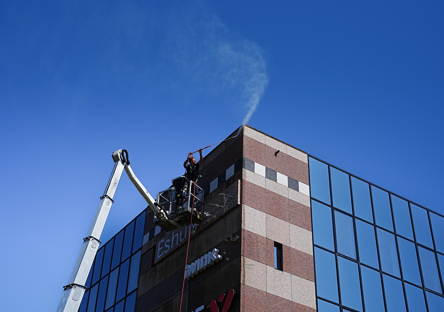 Wesko reinigt vanuit een hoogwerker de gevel van een bedrijfspand in Groningen.