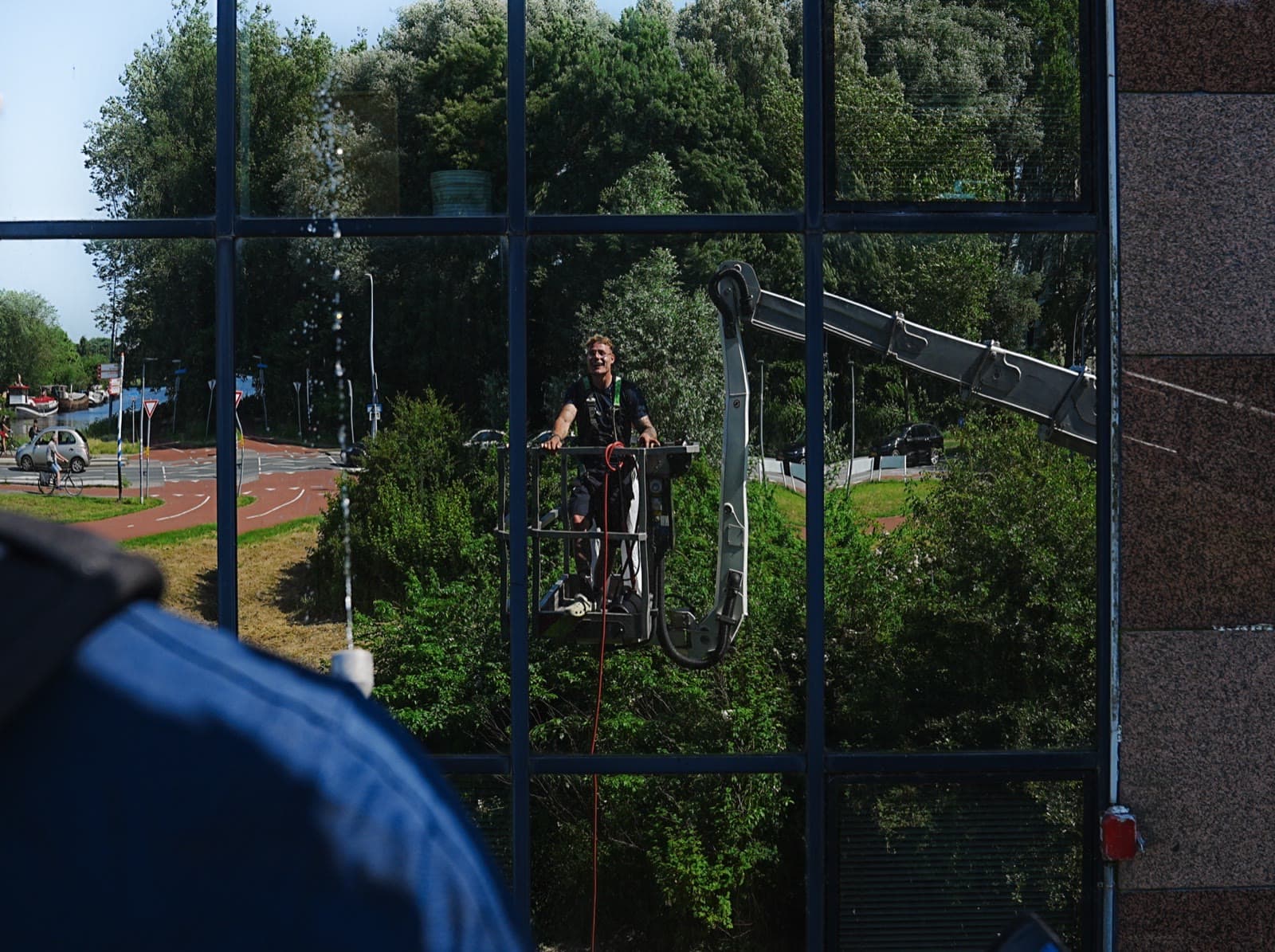 Wesko-medewerker werkt vanuit een hoogwerker aan de reiniging van een glazen gevel in Groningen.