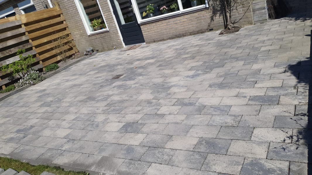 Hetzelfde betegelde terras met een zichtbaar schoner oppervlak na de reiniging.